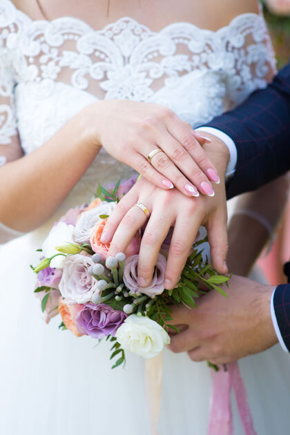 结婚戒指新娘和新郎的手放在婚礼花束上女人关系新婚夫妇