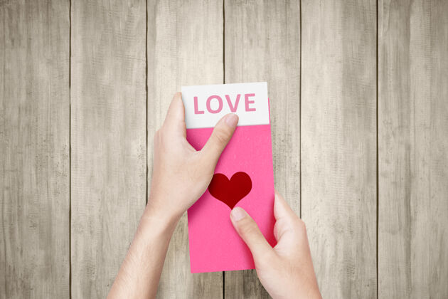 情人节人的手打开一个心形的粉红色信封 信封上写着爱的文字墙情人节礼物天哪节日日子情人节