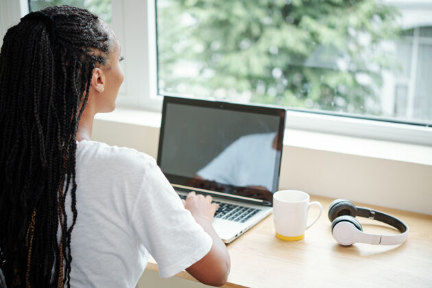 打字在笔记本电脑上工作了一整天 从窗户往外看之后 年轻女子正在享受短暂的休息教学编程职业