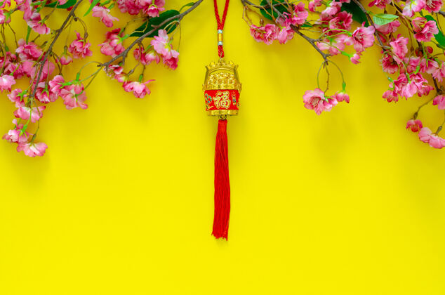 好吊坠为中国新年装饰（字的意思是财富）与中国花卉黄色背景花瓣文化流苏