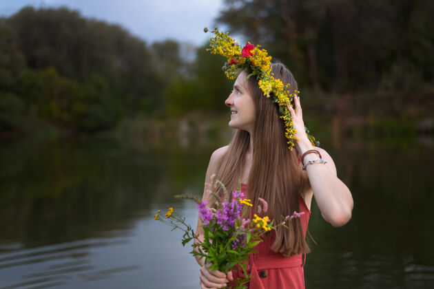 季节年轻漂亮的姑娘 留着长发 头戴花环花.肖像河湖背景上的花儿女孩乡村发型花