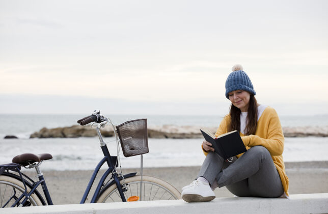 女孩坐在海边看书和骑自行车的女人道路人旅行