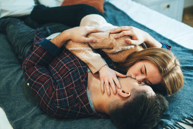 舒适美丽的年轻夫妇在家里靠在床上亲吻拥抱美丽谎言浪漫
