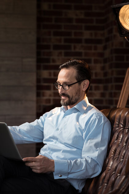 优雅需要工作快乐帅气时髦的男人拿着一台笔记本电脑 一边看着屏幕一边在书房里工作连接数码人