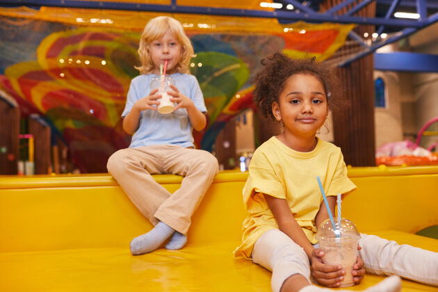 小两个小朋友在游戏中心休息时喝牛奶鸡尾酒牛奶乐趣娱乐