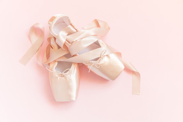 点鞋新粉彩米色芭蕾舞鞋与缎带隔离在粉红色的桌子上优雅排练职业