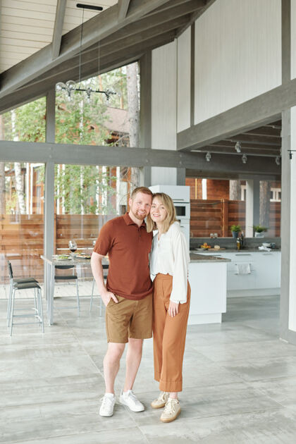 站着在小屋里 幸福美丽的夫妇拥抱在现代厨房的画像快乐成人成熟的男人