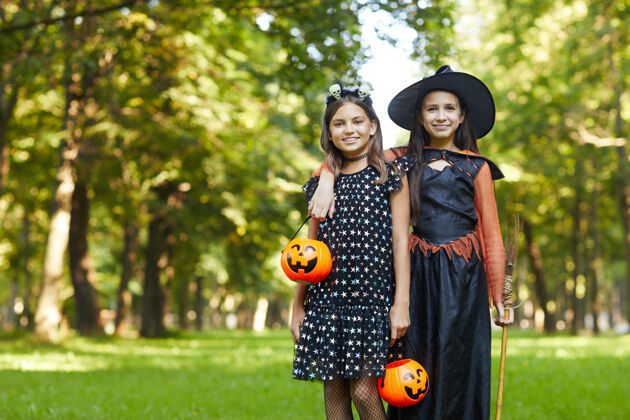 聚会社交活动两个穿着女巫服装的女孩站在公园外对着镜头微笑的画像魔术玩童年