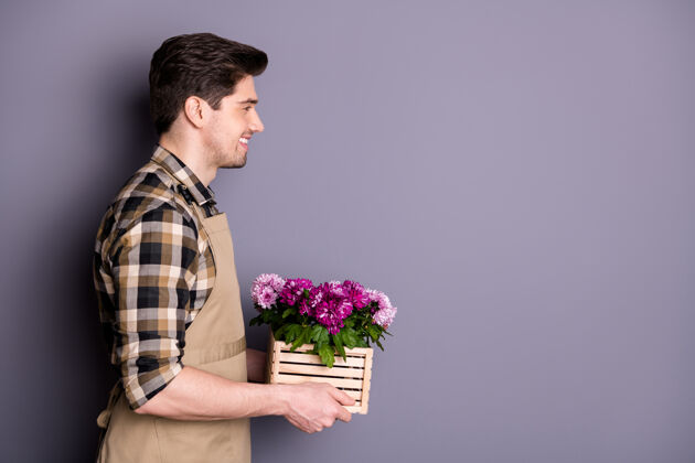 工作有魅力的工人小伙手牵手粉色花朵在花盆里生长建议购买鲜花避免修剪穿围裙格子衬衫隔离灰色墙壁商店业主服务
