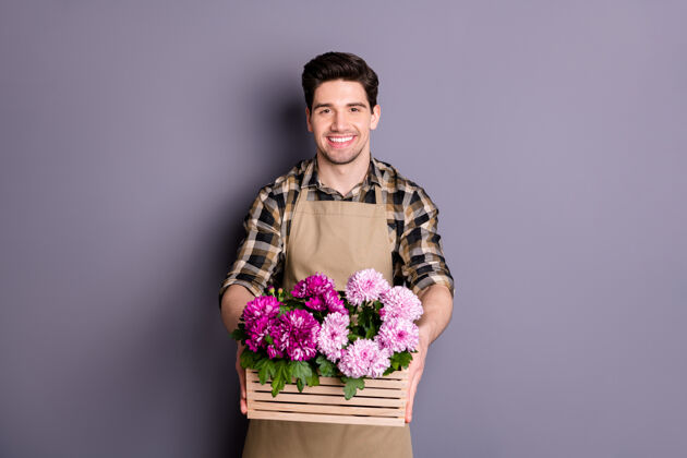 雇员照片中 开朗积极的男子牙牙学语地微笑着 作为花店送花员 奉命将鲜花送给你孤零零的灰色墙壁年轻企业家花店
