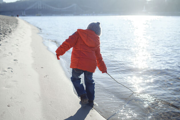 散步孩子们沿着河岸散步 享受冬日的阳光活动休闲寒冷