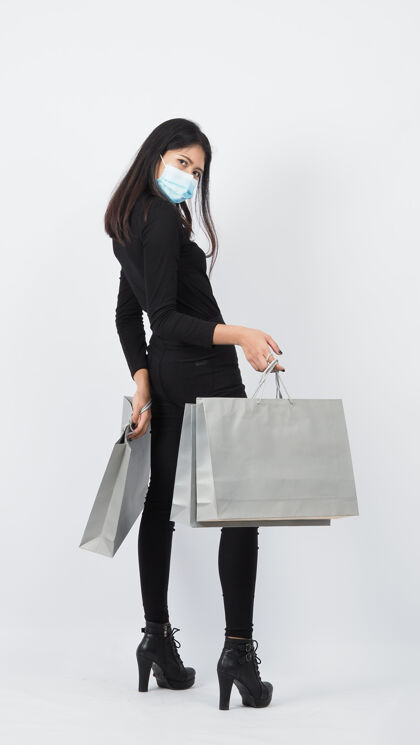 持有Covid19和购物亚洲概念戴口罩的女人在购物包女孩纸袋代表在冠状病毒危机或病毒性肝炎期间购物1.购物者还有病毒面具市场购买危机