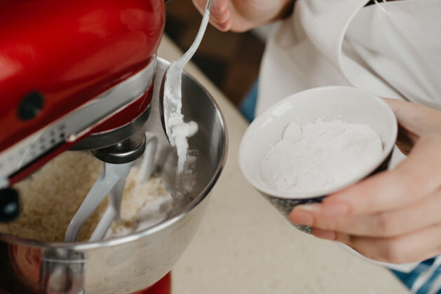 面粉一张糖粉的近照从勺子里掉到了正在搅拌酥皮糕点的红架子搅拌机的不锈钢碗里烹饪糕点自制