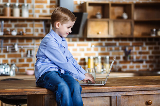 教育小男孩坐在桌子上用他的笔记本电脑过程快乐用户