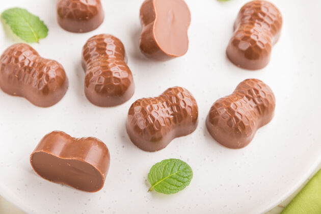 薄荷白色木质表面和绿色纺织品上的杏仁巧克力糖果巧克力糖果可可