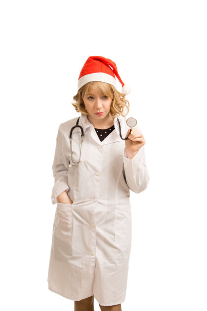 从业者美丽的年轻金发医生或护士 戴着圣诞老人帽 穿着睡衣 在医院庆祝圣诞节专家医生医生