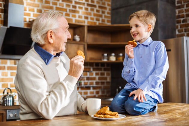 年轻人积极的老人和孙子一起吃自制饼干可爱孩子家庭