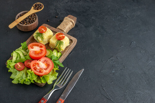 午餐切新鲜西红柿和黄瓜奶酪的特写镜头放在黑色表面右侧深色毛巾上的木板餐具上毛巾壁板盘子
