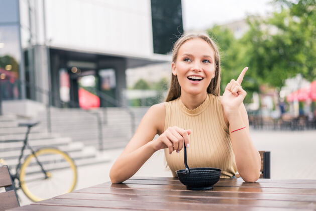 咖啡年輕美女在戶外咖啡廳吃沙拉時用手指做手勢現代晚餐人