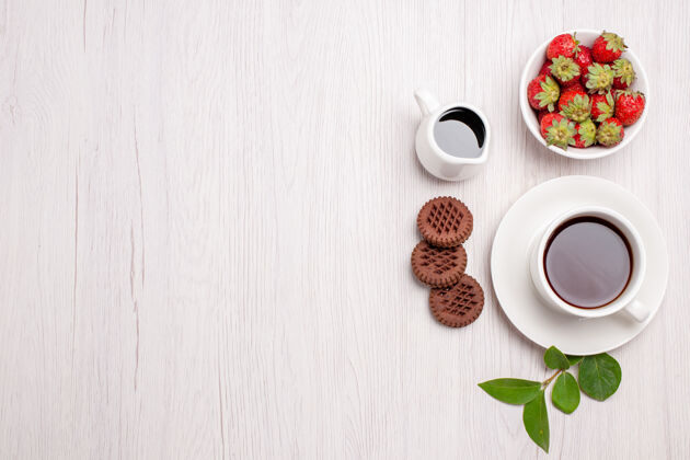 桌子顶视图一杯茶 上面放着饼干和草莓 桌上放着白糖茶饼干 甜甜饼干咖啡热的酒精
