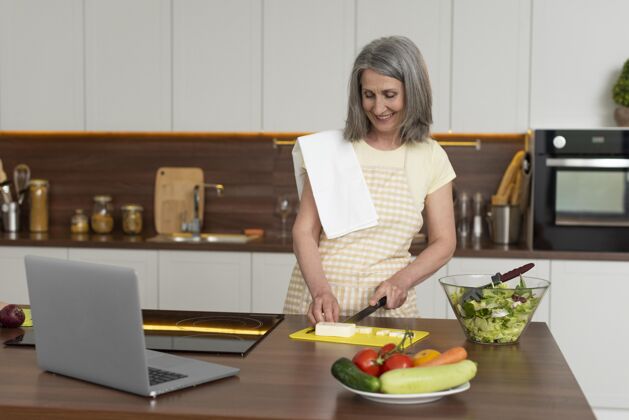 养老金家里的老太太在厨房用笔记本电脑上烹饪课厨房老年人家庭