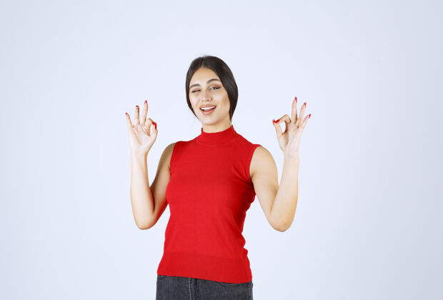 姿势穿红衬衫的女孩显示出积极的手势好雇员员工