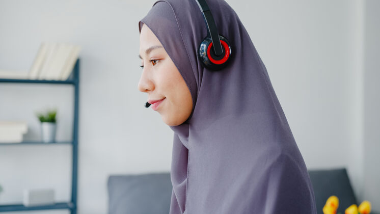 社交亚洲女士戴着耳机看网络研讨会听在线课程在家里通过电话会议视频沟通团队耳机头巾