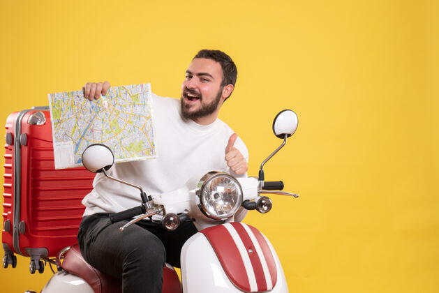 地图旅行的概念与微笑的家伙坐在摩托车上 手提箱上显示地图 使黄色的ok手势车辆人黄色