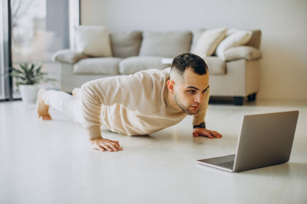 健身年轻的运动型男子在家练习瑜伽电脑工作男性