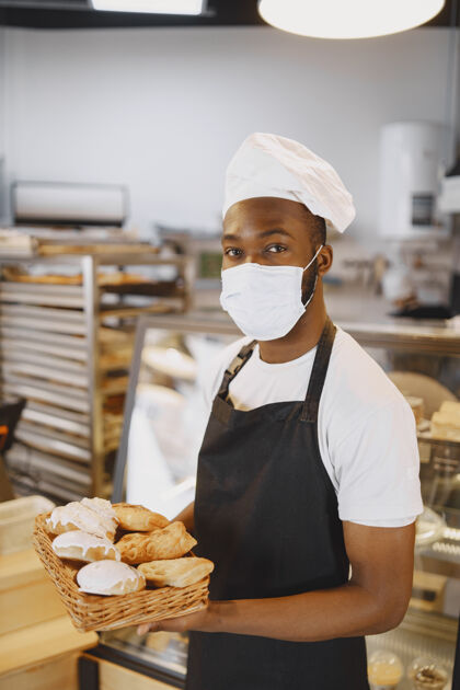 面包非洲裔美国面包师和新鲜面包在面包店的肖像糕点厨师拿着小糕点非洲商业柜台