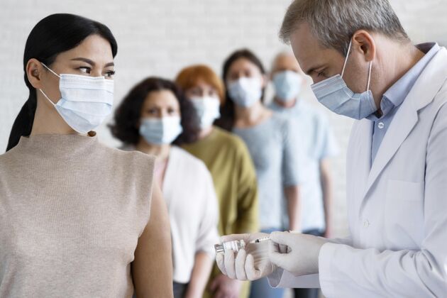 女人戴着医用口罩的男医生注射疫苗的女人注射疫苗免疫