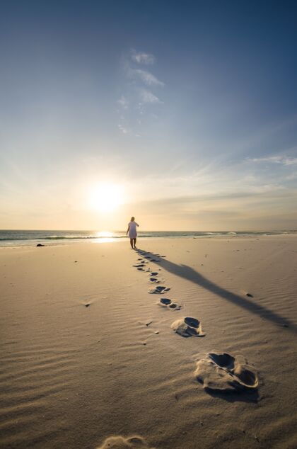 人垂直拍摄一个人走在沙滩上的足迹前景海洋海岸阳光