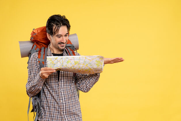 地图正面图年轻男子背着背包徒步旅行黄色背景森林公司观察地图旅行自然色空气旅行公司自然