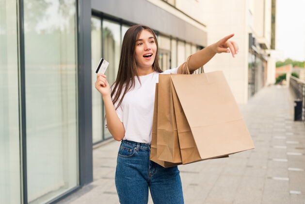 金钱销售 购物 旅游和快乐的人的概念-美丽的女人与购物袋和信用卡在一条街上的手购物买家女性