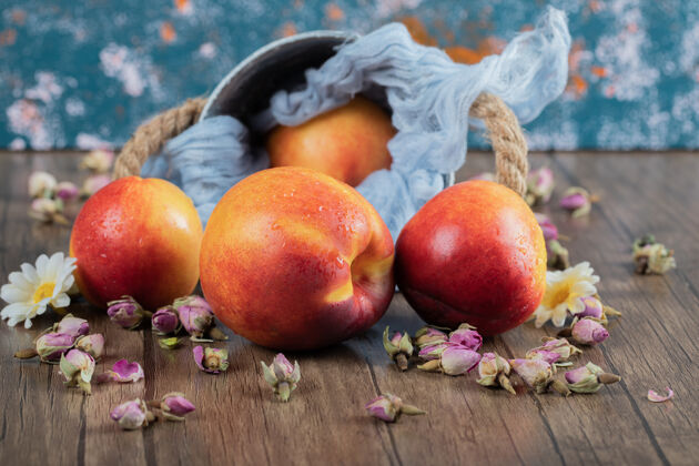 新鲜红色和黄色的桃子放在毛巾上的蓝色金属桶上产品食物水果