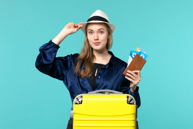 微笑前视图年轻女子拿着她的票 准备在淡蓝色背景下旅行旅行旅行飞机海上度假旅行人秘书年轻女子