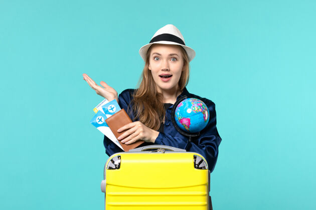 专业正面图年轻女子手持机票和地球仪上蓝色背景的飞机远航海上度假之旅肖像旅程票