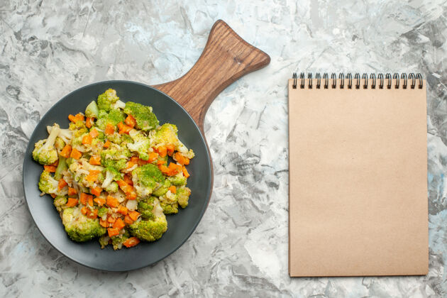 肉木砧板上的新鲜健康蔬菜沙拉和白桌子上的笔记本俯视图新鲜食物切