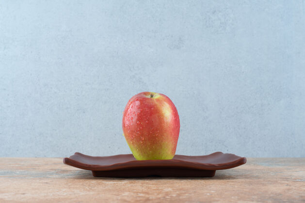 深色一整只红甜苹果放在深色盘子里可口水果食物