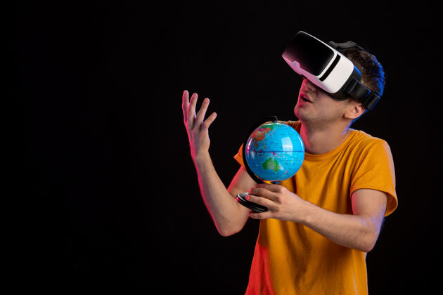 成人在黑暗的表面上玩虚拟现实拿着地球仪的年轻男性男人玩家现实