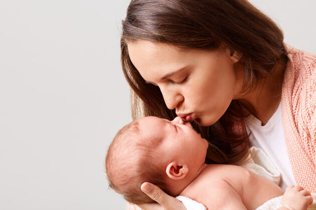 纽带可爱的女人闭着眼睛亲吻她的新生婴儿的特写照片爱亲吻女性