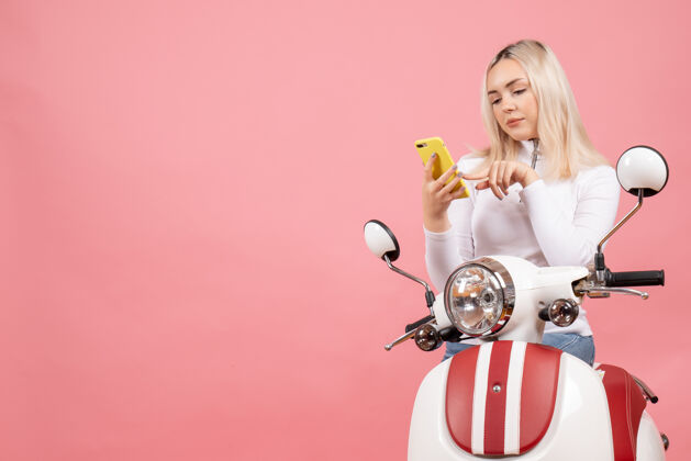 唐菖蒲前视图：坐在轻便摩托车上看电话的年轻女士小姐快乐时尚