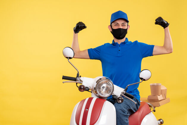 年轻男性信使正面图身穿蓝色制服的年轻男性快递员在黄色背景上工作-快递服务-自行车工作视图传送带人