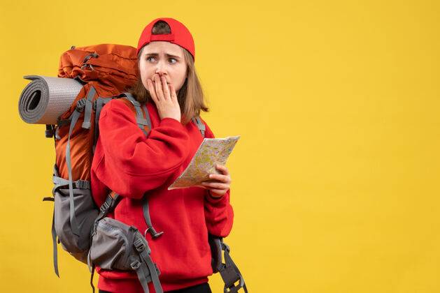 背包前视图忧心忡忡的女徒步旅行者拿着红色背包的地图前面成人地图