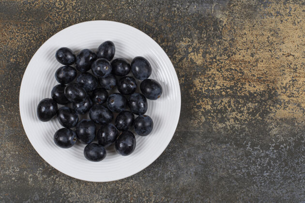 浆果白盘子里放着新鲜的黑葡萄葡萄水果美味