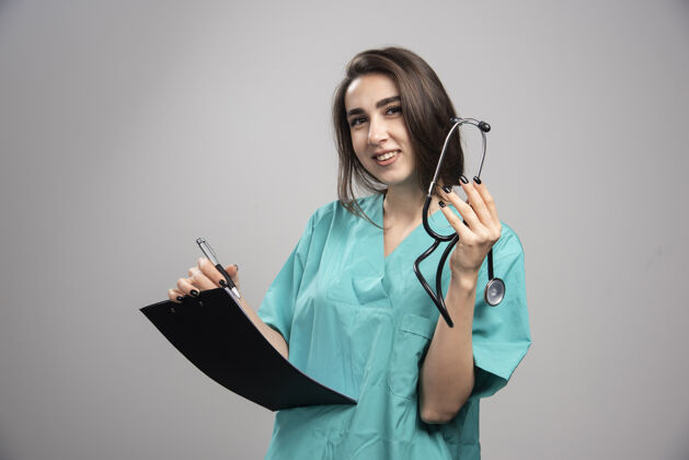 疾病微笑的医生手持听诊器在灰色背景下高品质的照片医院医生工作