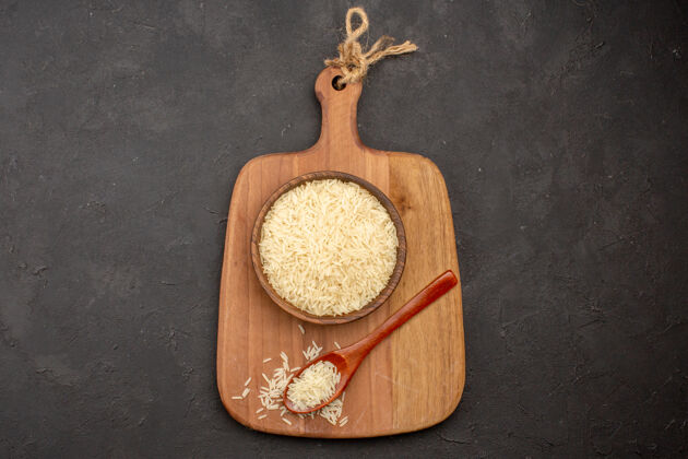 健康在灰色表面的木制棕色板内的生大米俯视图大米生烹饪