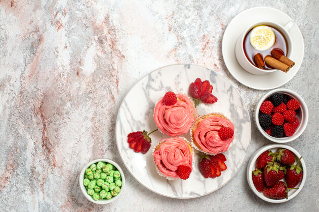 早餐粉红色草莓蛋糕的俯视图 白色表面上有一杯茶自封饼干桌子