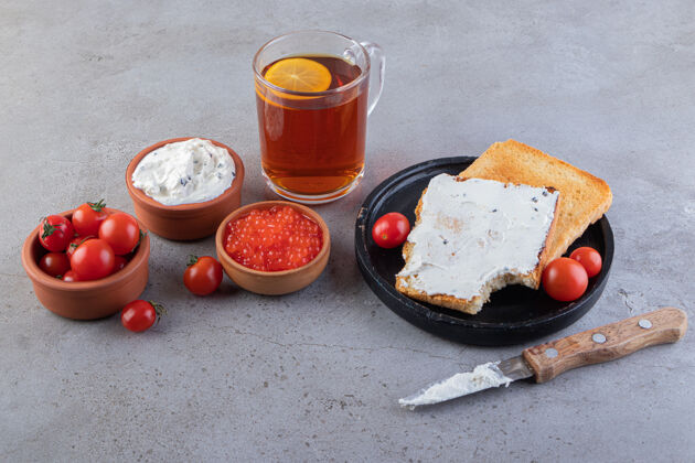 蔬菜在大理石上放上黄油和新鲜红樱桃西红柿的油炸烤面包食物黄油红色