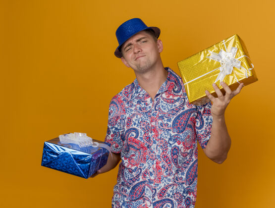 蓝色一个戴着蓝帽子 拿着礼品盒 孤零零地站在橘子上的年轻人派对男人橙色
